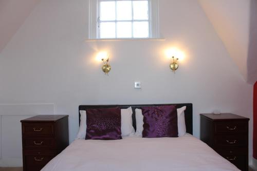 彼索普斯托福The George Hotel Stansted Airport的一间卧室配有一张带紫色枕头的床和窗户。