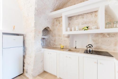 奥斯图尼Casa Zio Piero的厨房配有白色橱柜和石墙