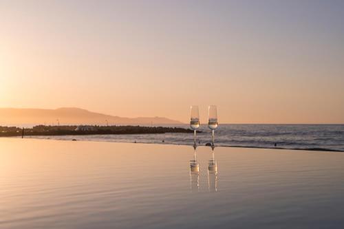 普拉塔尼亚斯玛丽卡酒店 的日落时坐在海滩上的两杯酒