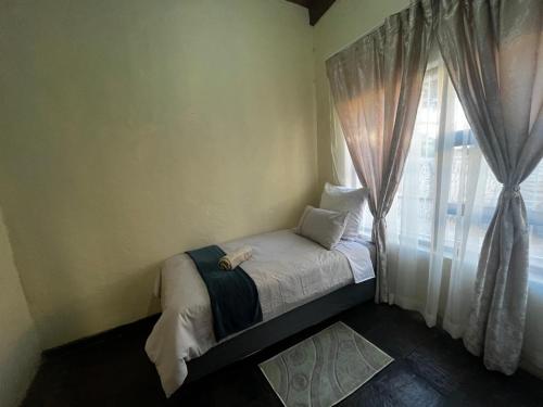 比勒陀利亚Mbobo Legacy Residence的窗户客房内的小床