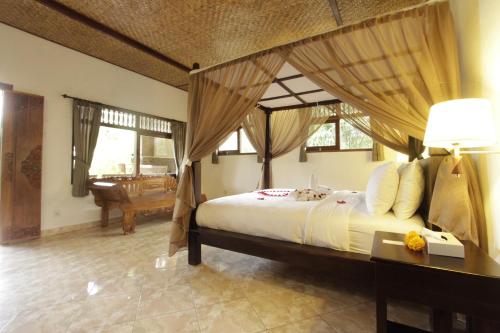 乌布裴卡科曼库旅馆的一间卧室配有一张带天蓬的大床