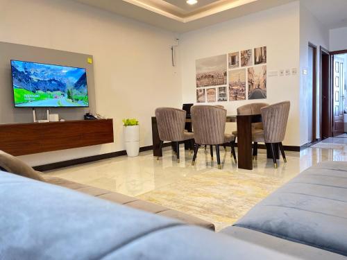 代希瓦勒Green Star City Apartment的用餐室配有桌椅和平面电视。