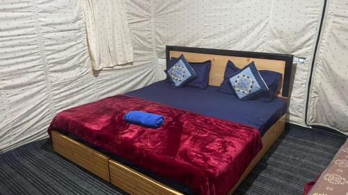 马拉里Zaranka Camps Kasol的一张带红毯和蓝色枕头的床
