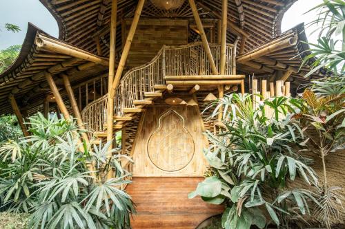 SelatMagic Hills Bali - Magical Eco-Luxury Lodge的植物中间有木楼梯的房子