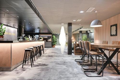 万塔Comfort Hotel Xpress Helsinki Airport Terminal的餐厅设有酒吧,配有椅子和桌子