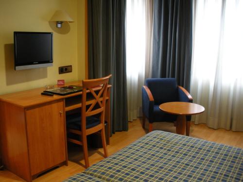 马德里马德里卡斯蒂拉斯二世酒店的酒店客房配有书桌、床和电视。