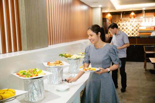 胡志明市Golden Dragon Hotel Sai Gon的餐馆里拿着一盘食物的女人
