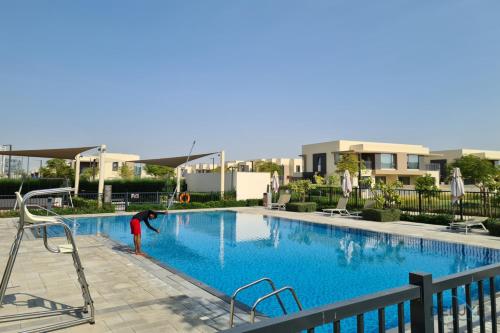 迪拜Charming 4BR Villa with Assistant Room in Dubai Hills Estate by Deluxe Holiday Homes的一个人在游泳池玩耍