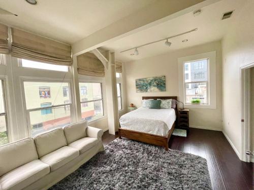 旧金山LUXE Lower Nob Hill Penthouse - Sleeps 6的一间卧室配有一张床、一张沙发和窗户。