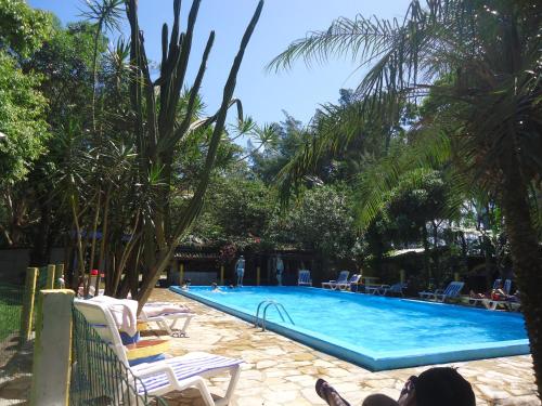 因贝Pousada Fazendinha Tatuira的棕榈树泳池,人们躺在泳池旁的椅子上