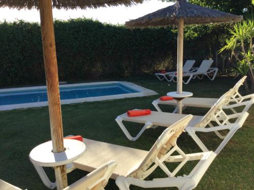 塞特尼尔Casa Rural Las Bodegas的游泳池旁的两把椅子和一把遮阳伞