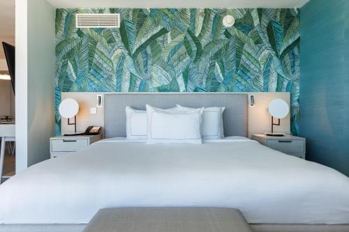 圣胡安Condado Palm Inn San Juan, Tapestry Collection by Hilton的一间卧室配有一张白色大床,铺有热带壁纸
