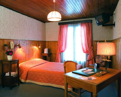 热克斯Logis Hôtel La Petite Chaumière的一间卧室配有一张床、一张书桌和一个窗户。