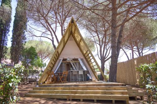 卡帕尔比奥Costa D'Argento - Camping Village Club Capalbio的森林中带楼梯和门廊的框架房屋