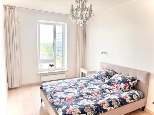里加Skanstes Apartment Free Parking的一间卧室配有一张带花卉棉被的床和窗户。