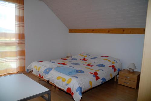 Les Geneveys-sur-CoffraneAppartment Aux Lilas的一间卧室配有一张带床罩的床和窗户