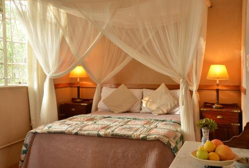 ChobeMuchenje Self Catering Cottages的一间卧室配有一张带窗帘和水果的床铺。