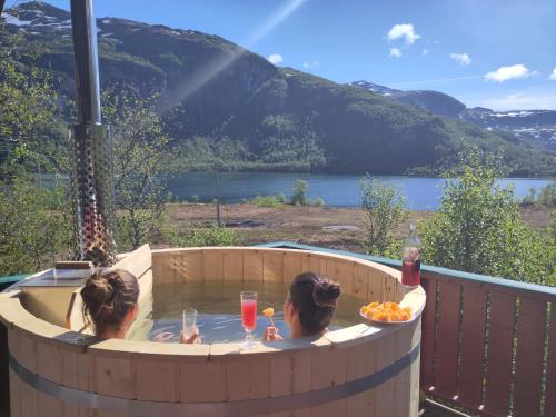 米达尔Reinunga Eco Hytta - Mountain lodge near Myrdal accessible only by train or bike的两个女孩坐在热水浴缸里喝一杯