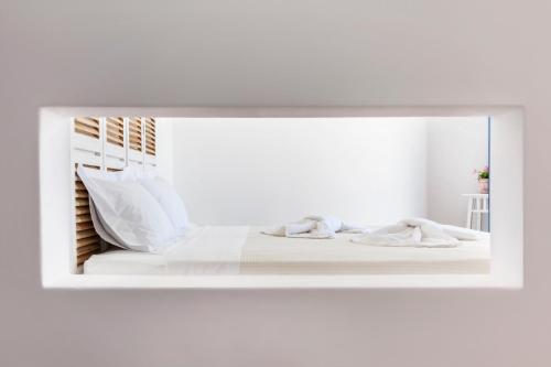乔拉弗雷恩多斯Aegeo Hotel的镜子反射着白色床单和枕头的床