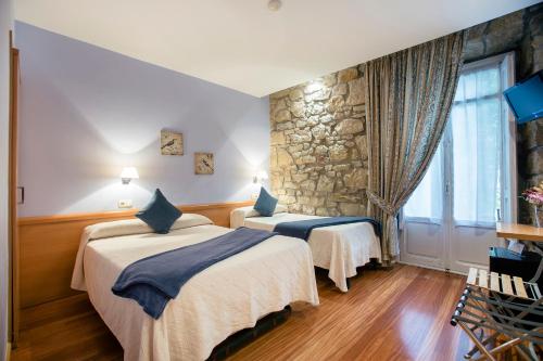 圣塞瓦斯蒂安新艺术膳食公寓的酒店客房设有两张床和石墙。