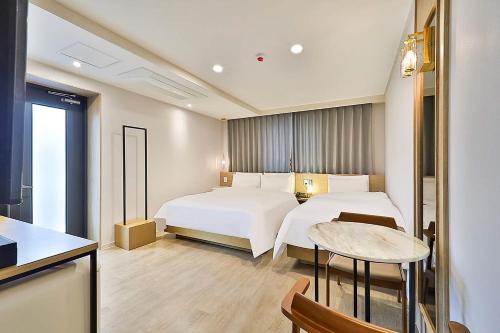 蔚山Rubato Hotel Ulsan Junggu的酒店客房设有两张床和一张桌子。