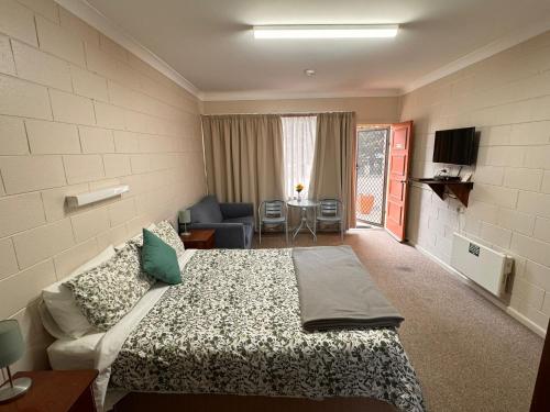 库马ALPINE COUNTRY MOTEL and METRO ROADHOUSE COOMA的一间卧室设有一张床和一间客厅。