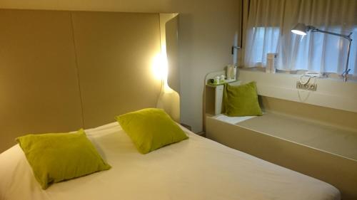 巴约讷钟楼巴永娜酒店的一间卧室配有一张带黄色枕头的床和一扇窗户