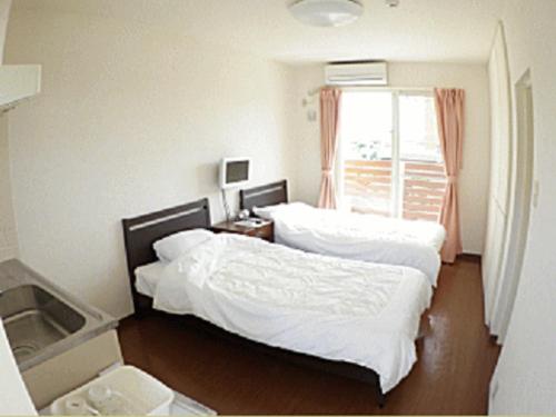 座间味村茶别墅酒店的一间卧室设有两张床和窗户。