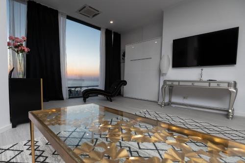 康斯坦察Maritimo Luxury ApartHotel的客厅配有玻璃桌和电视