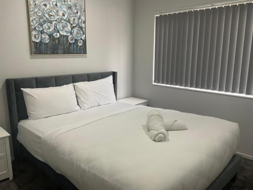 奥克兰Family Holiday Home Papakura - 175的一只泰迪熊躺在卧室的床上