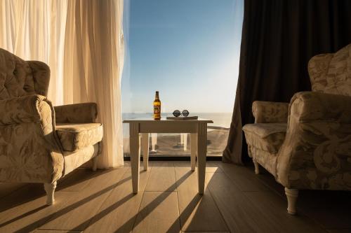 康斯坦察Maritimo Luxury ApartHotel的一间设有两把椅子和一张桌子的房间和一瓶葡萄酒
