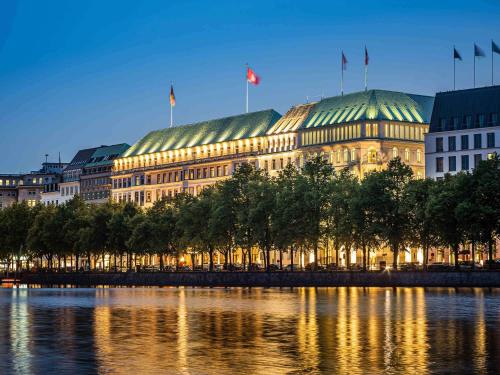 汉堡Fairmont Hotel Vier Jahreszeiten, Hotel des Jahres 2023 & 2024- Die 101 Besten的一座在河上悬挂旗帜的建筑物