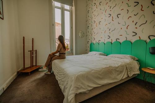 蒙得维的亚Viajero Montevideo Hostel的坐在床上看着窗外的女人