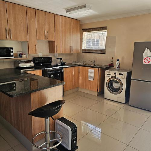 逊邱伦Marigold Self Catering Apartment的厨房配有木制橱柜、洗衣机和烘干机