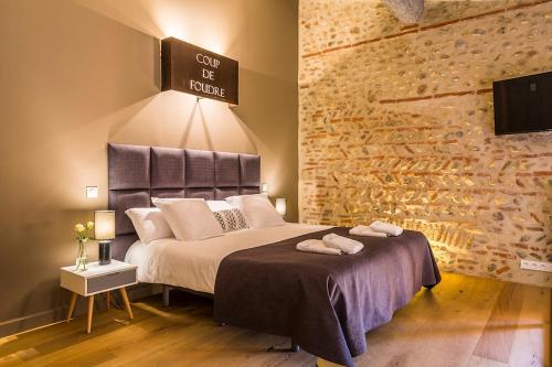 佩皮尼昂马斯拉图尔纳维尔酒店的一间卧室配有一张大床,上面有标志