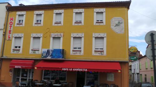 Carmaux勒甘贝塔酒店 的一条黄色的建筑,在街上有红色遮阳篷