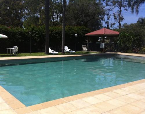 麦夸里港艾奇沃特假日公园酒店的一个带椅子和凉亭的大型蓝色游泳池
