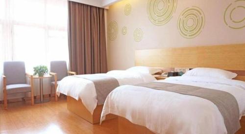 共青城GreenTree Inn Express Gongqing City Nanchang University的酒店客房,配有两张床和椅子