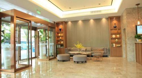 上海Home Inn Plus Shanghai Middle Ring Jinshajiang Road Fengzhuang Metro Station的大楼的大堂,配有桌椅