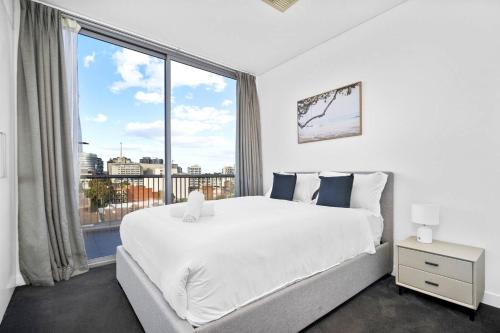 悉尼2BR Luxury Stay in Ultimo的卧室设有一张白色大床和大窗户
