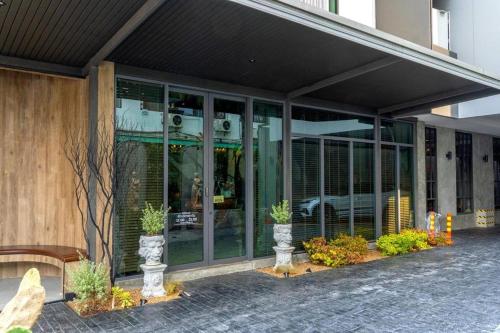 曼谷J PLACE HOTEL的一座建筑,前面有玻璃门和植物