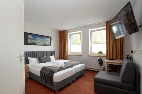 吕贝克Baltic Hotel Lübeck的一间卧室配有一张床、一张沙发和一台电视