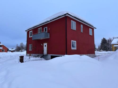 LillhärdalHärjulfs hus的雪中的一个红色建筑,周围积雪