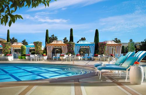 拉斯维加斯拉斯维加斯永利酒店的一座带蓝色桌椅的游泳池以及一座建筑