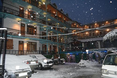 马拉里Hotel Neelgiri - Manali Diaries的大楼前的雪地停车场