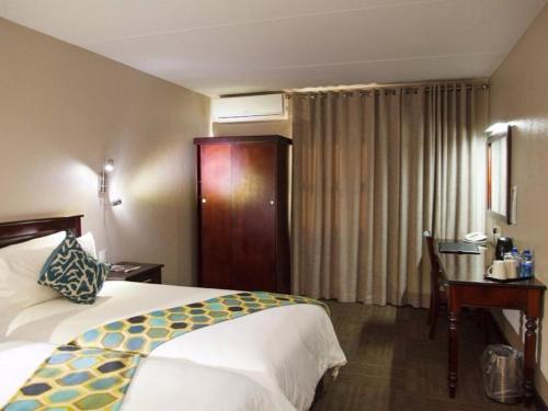 白河Hotel 247 @ White River的配有一张床和一张书桌的酒店客房