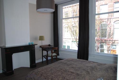 海牙欧泊里齐特斯特拉特住宿加早餐旅馆的一间卧室配有一张床、一张书桌和一个窗户。