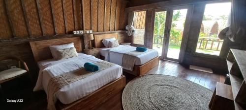 乌鲁瓦图Batu Jaran Hill Cottage Uluwatu的一间卧室设有两张床和大窗户