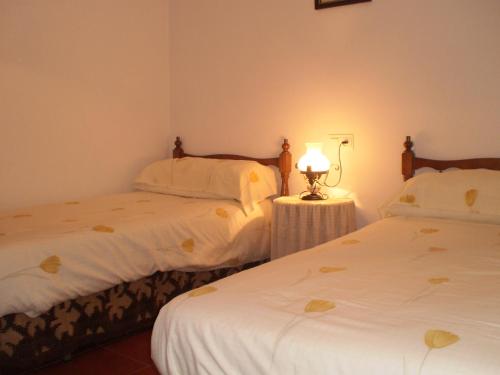 比纽埃拉La Atalaya de Los Romanes的一间卧室设有两张床和一张桌子上的台灯。
