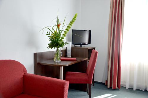 美因茨罗莫沃尔酒店的一间设有一张桌子、一台电视和花瓶的房间